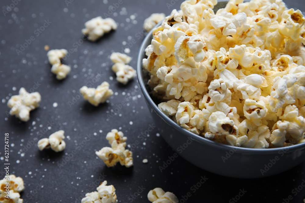 Bowl with tasty popcorn on black background