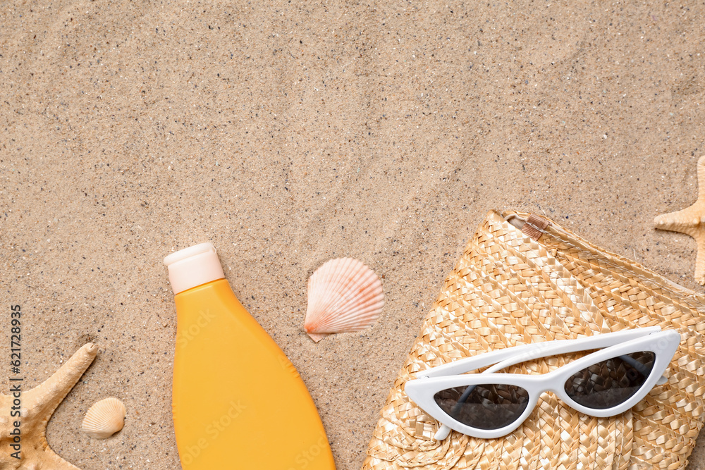 Sunglasses with wicker bag, starfishes and bottle of sunscreen cream on sand