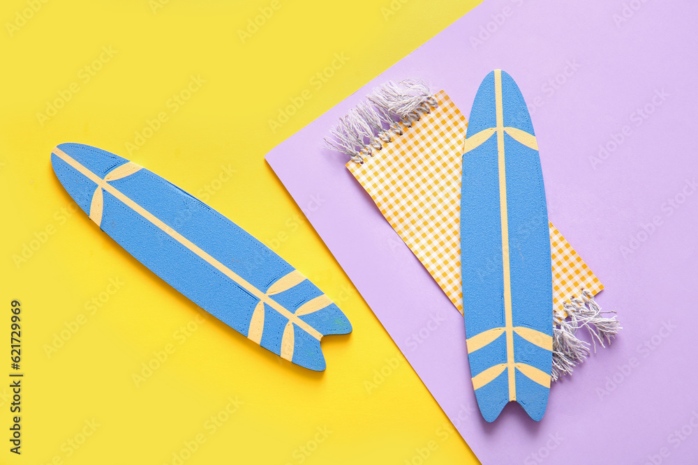 Mini surfboards with beach blanket on color background