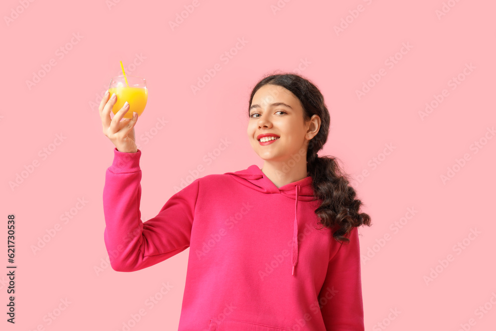 Teenage girl with glass of orange juice on pink background