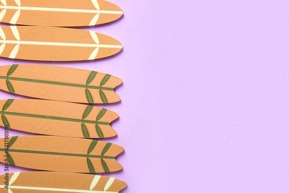 Many different mini surfboards on lilac background