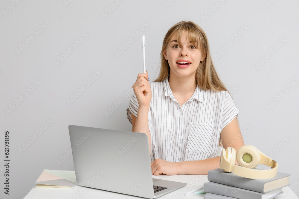 Female student pointing at something on light background