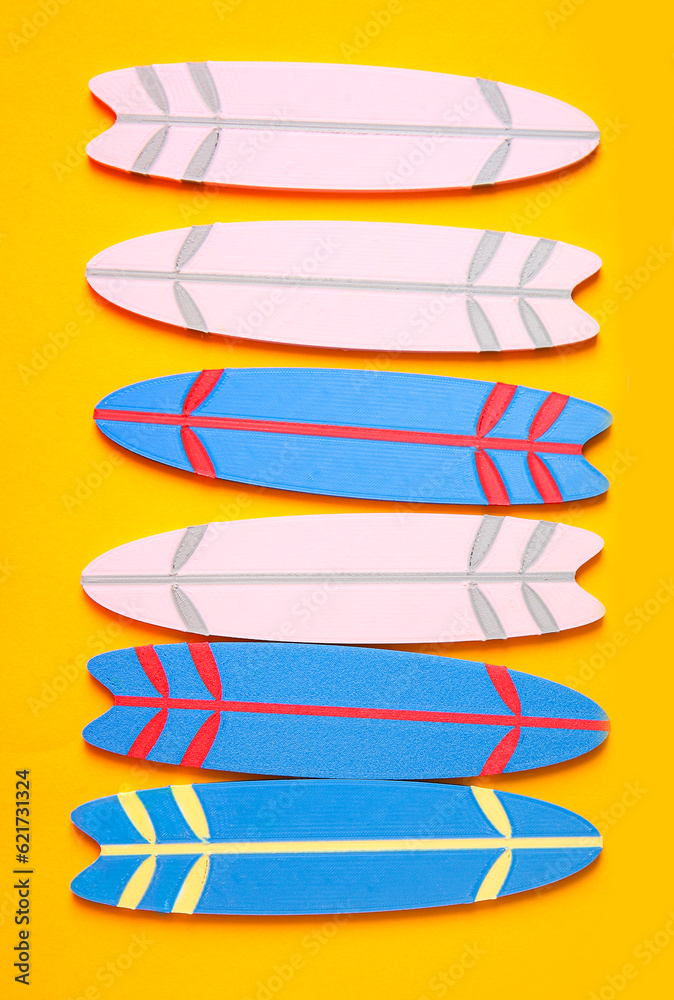 Many different mini surfboards on yellow background