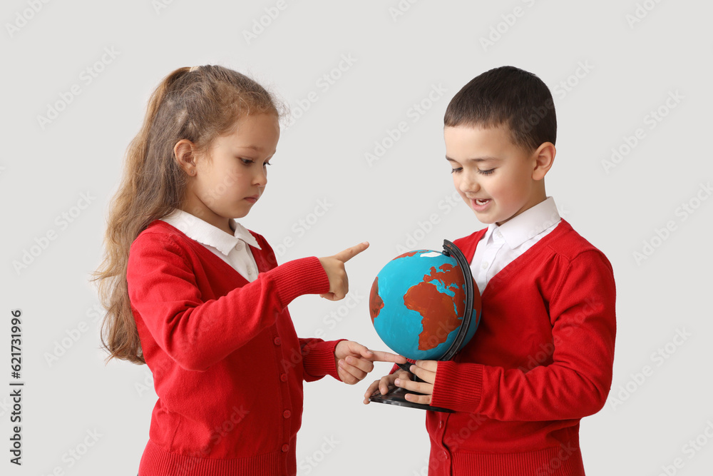 Little schoolchildren with globe on grey background