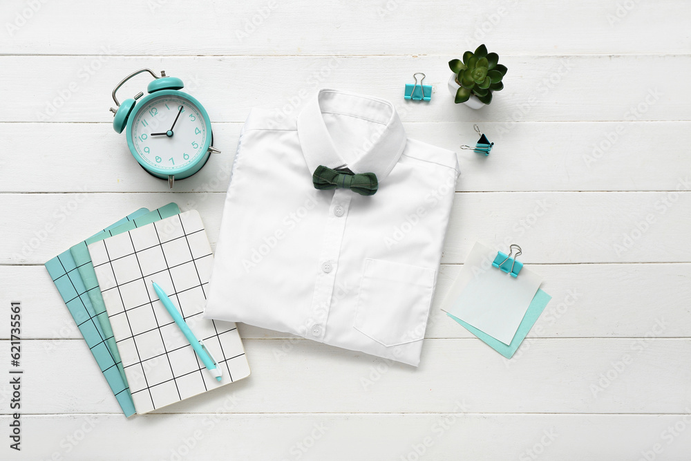 Different stationery with alarm clock and stylish school uniform on white wooden background