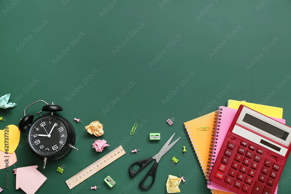 Alarm clock with calculator and different stationery on green chalkboard