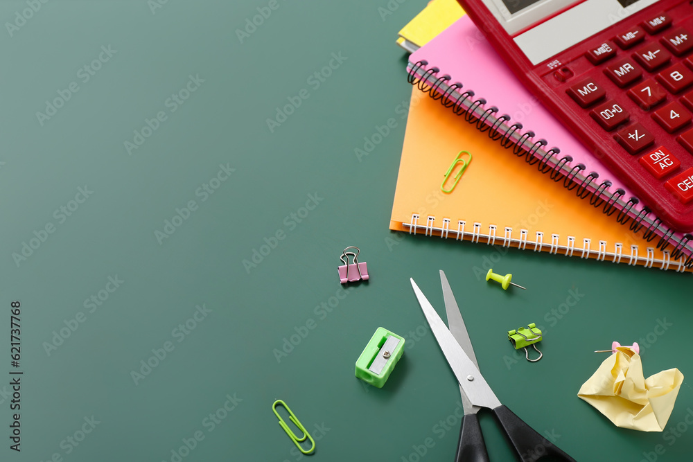 Calculator and different stationery on green chalkboard