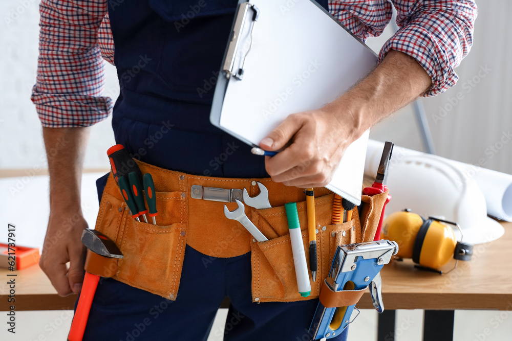 Male builder with clipboard in room, closeup