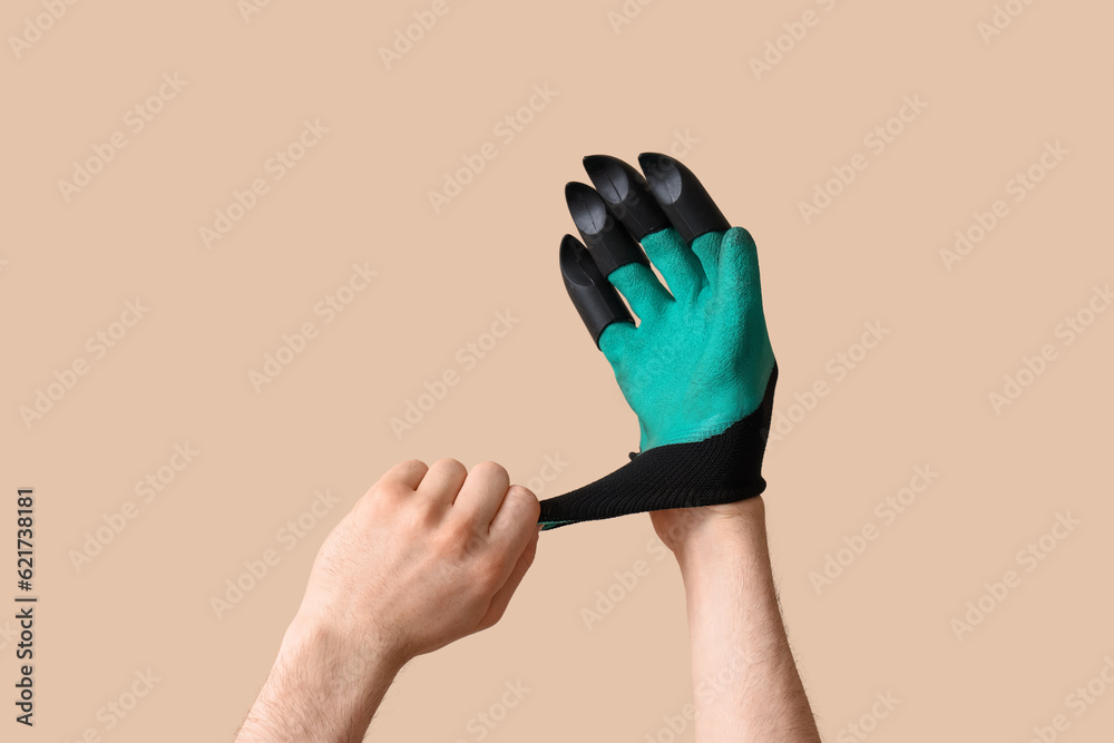 Gardener putting glove on beige background