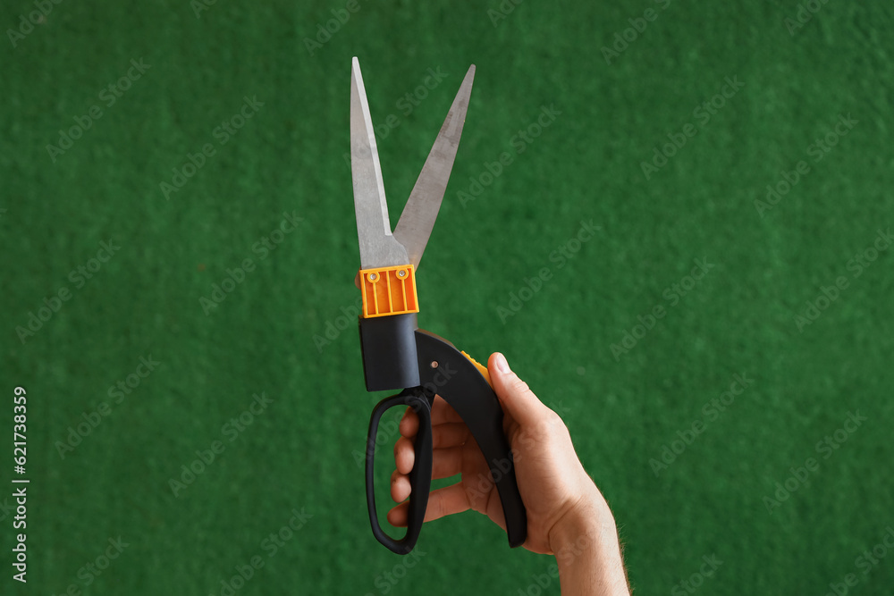 Gardener with secateurs on blurred green background