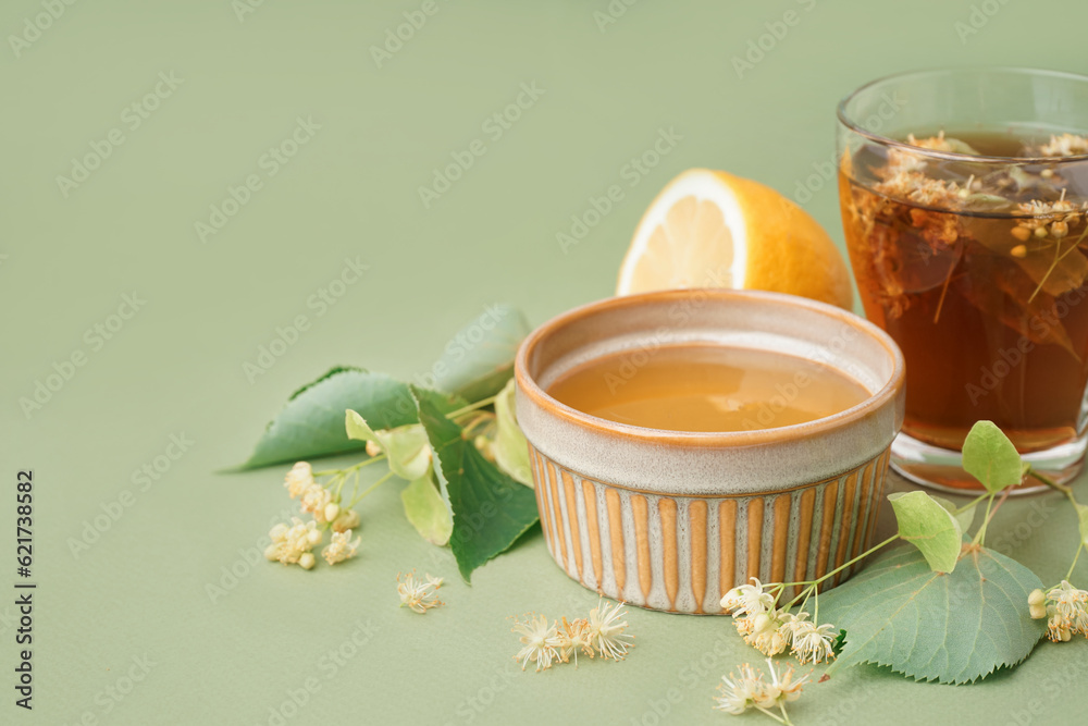 Bowl with linden honey and glass cup of tea on green background