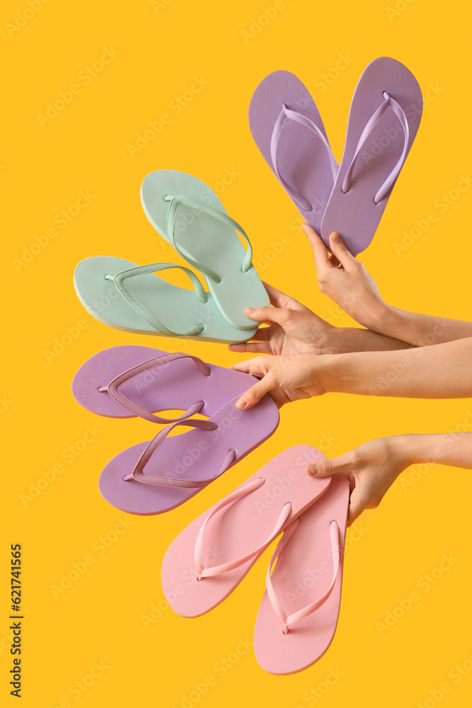 Hands with many different flip-flops on yellow background