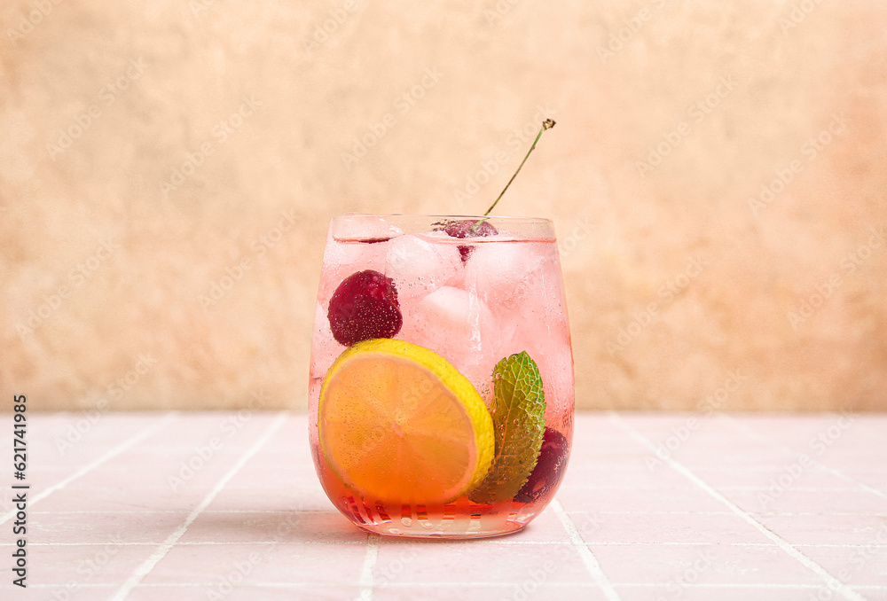 Glass of tasty cherry lemonade with lime and mint on pink tile table