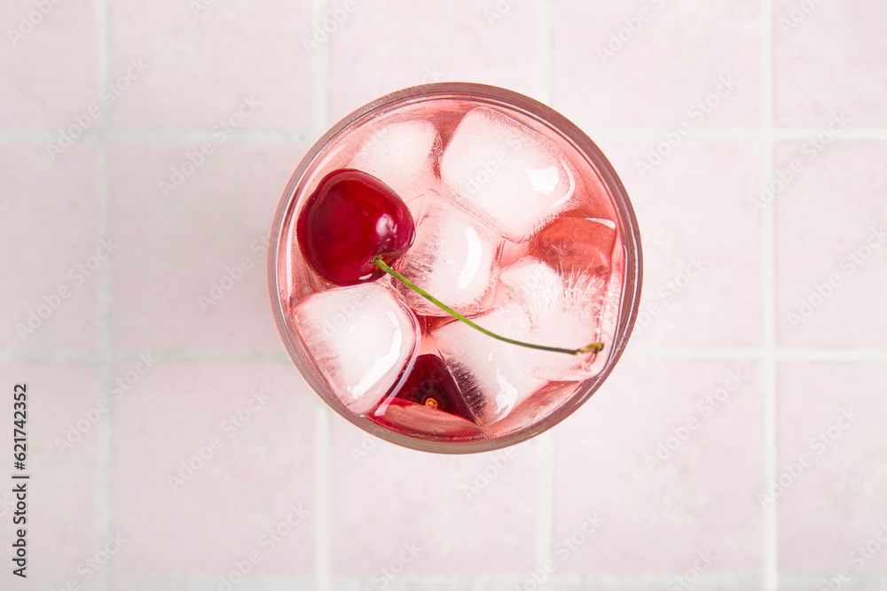 Glass of tasty cherry lemonade on pink tile background