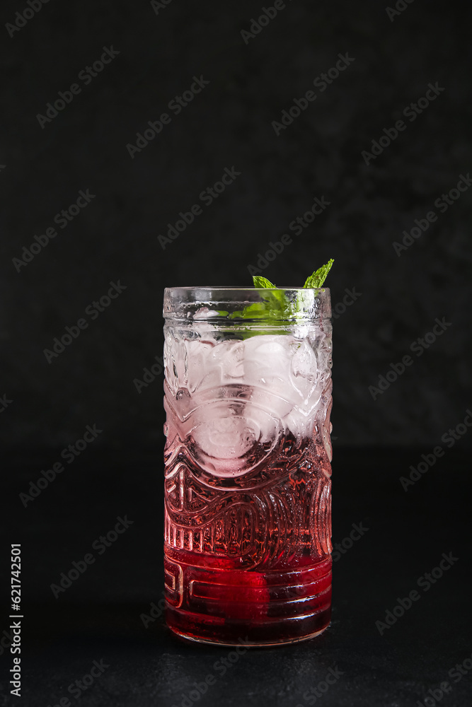 Glass of tasty cherry lemonade with mint on black background