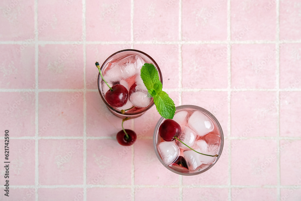 Glasses of tasty cherry lemonade with mint on pink tile background