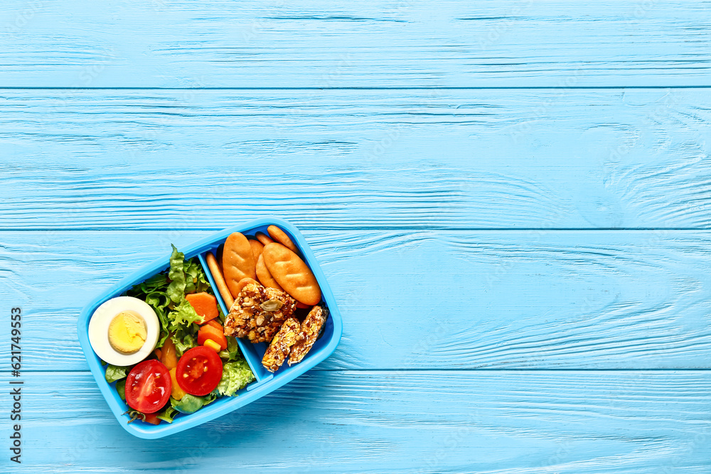 Lunchbox with tasty food on blue wooden background