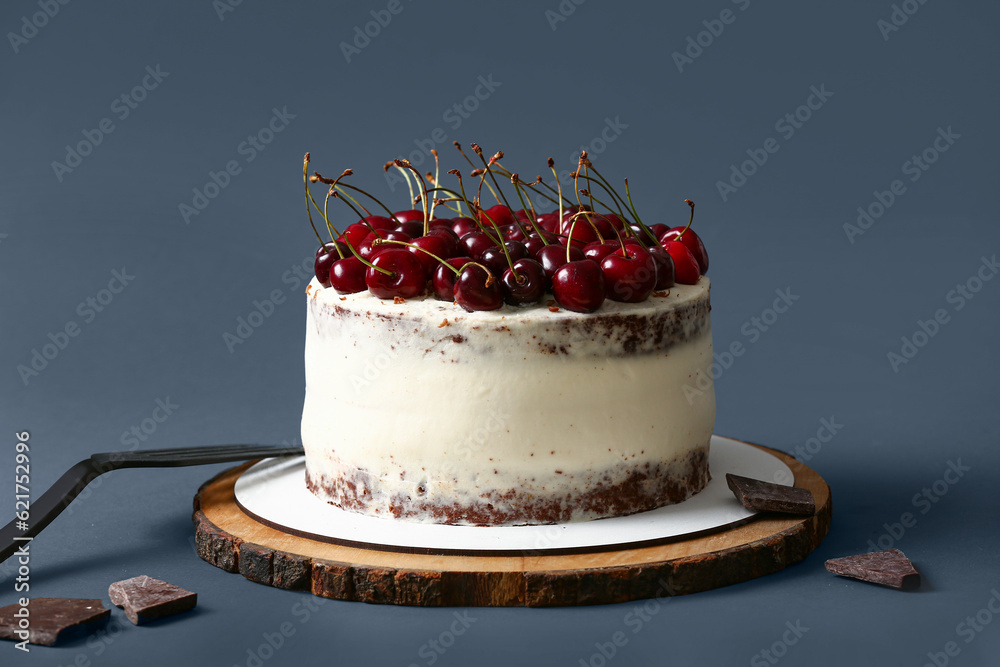 Wooden board with tasty cherry cake on dark background