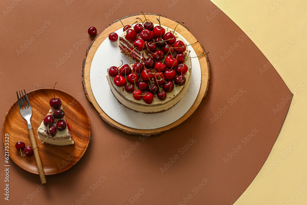 Plate and wooden board with tasty cherry cake on color background