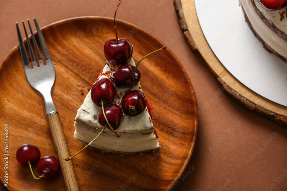 Plate with piece of tasty cherry cake on brown background