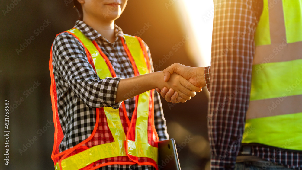 Close up hand of Female engineer in protective helmets and wear reflective safety clothing are shaki