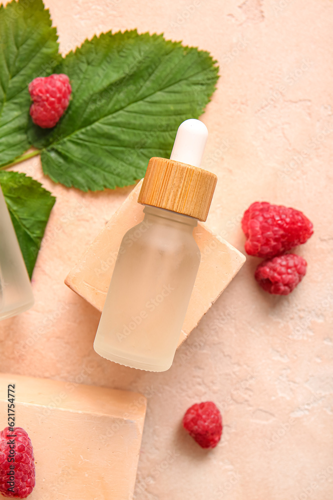 Decorative podium with bottle of cosmetic raspberry oil on pink background