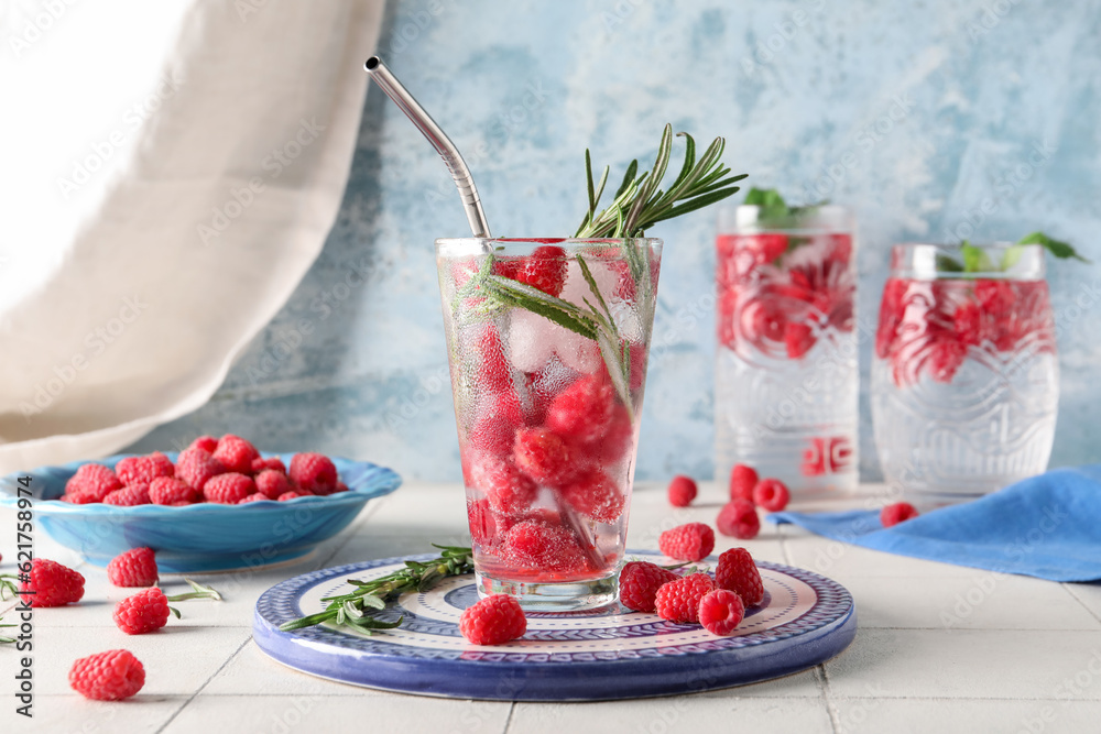 Glasses of fresh raspberry lemonade with rosemary on white tile table