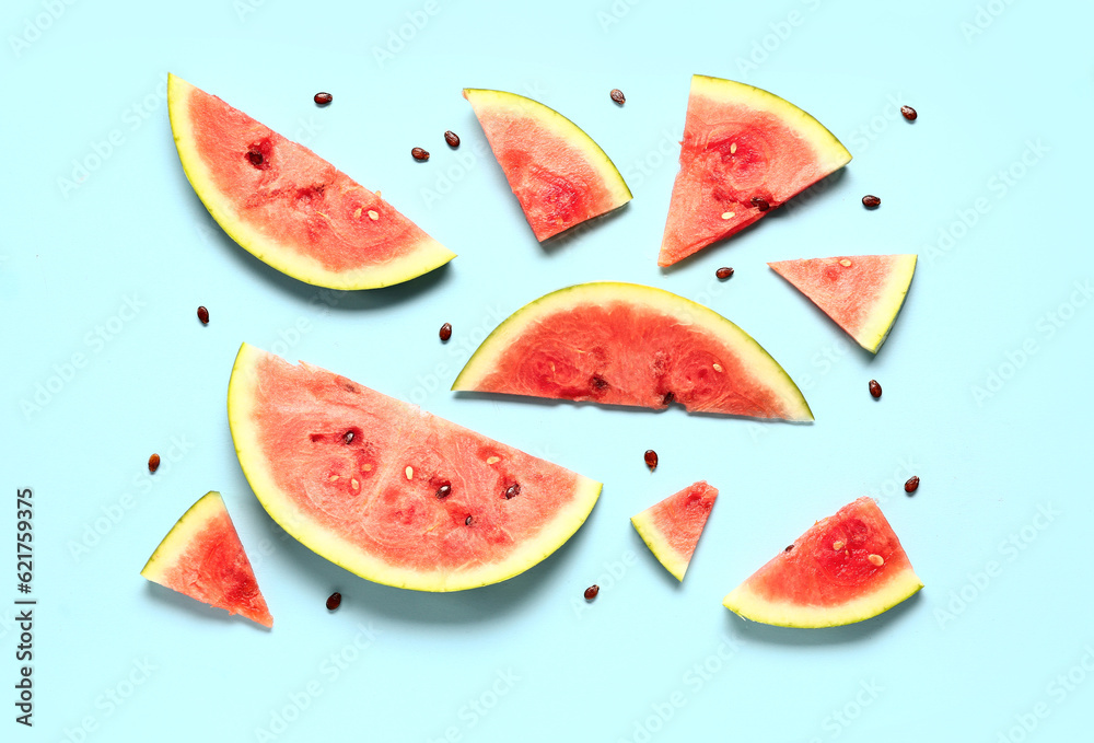 Pieces of fresh watermelon and seeds on blue background