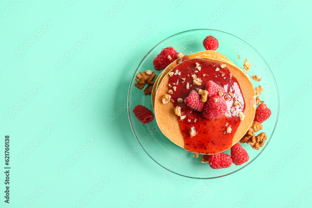 Plate of tasty pancakes with raspberries and nuts on turquoise background