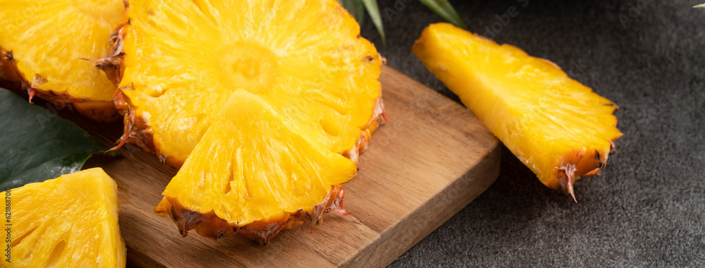 Fresh cut sliced pineapple in a plate over dark gray table background.