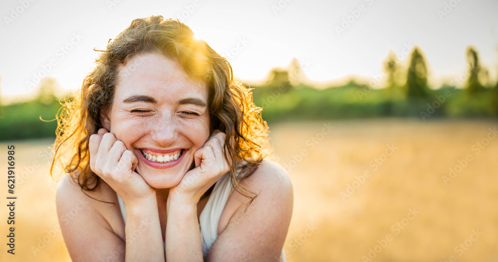 Happy beautiful woman smiling in a wheat field - Delightful female enjoying summertime sunny day out