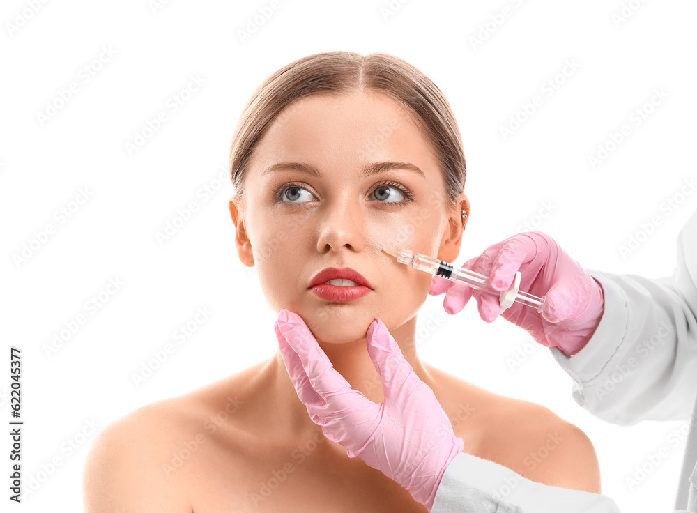 Young woman receiving filler injection in face against white background