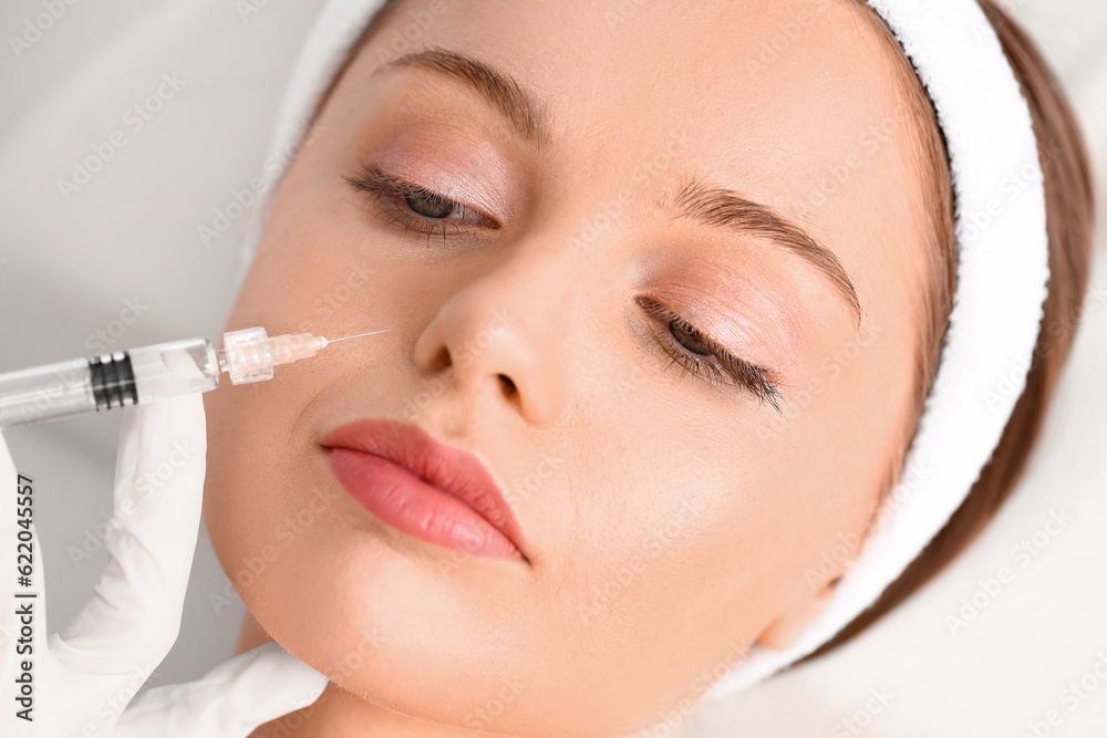 Young woman receiving filler injection  in beauty salon