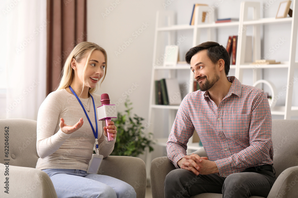 Female journalist with microphone having an interview with man in studio