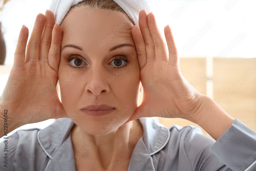 Mature woman doing face building exercise in bathroom, closeup