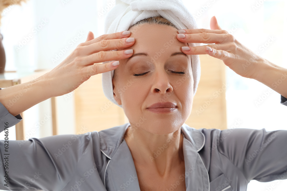 Mature woman doing face building exercise in bathroom, closeup