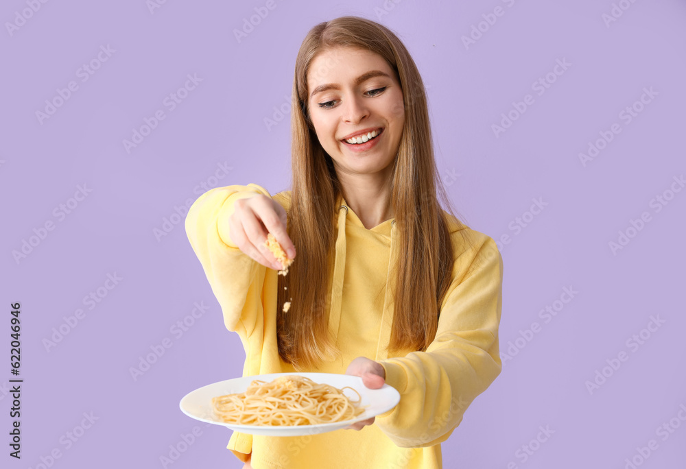 Young woman with tasty pasta on lilac background