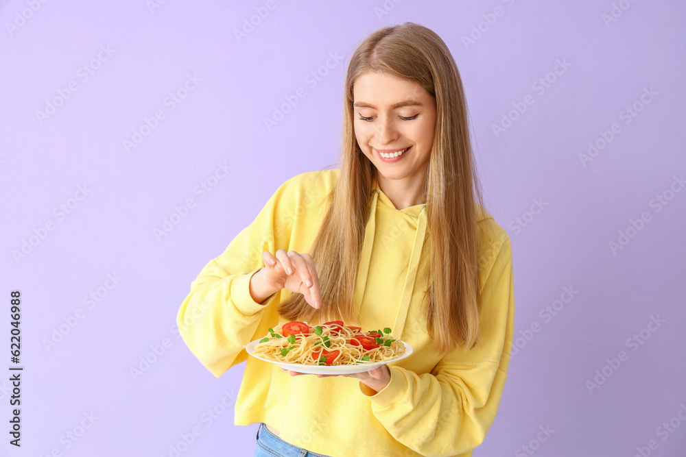 Young woman with tasty pasta on lilac background