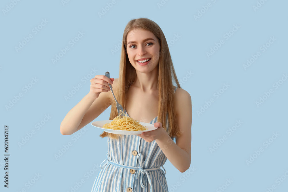 Young woman with tasty pasta on blue background