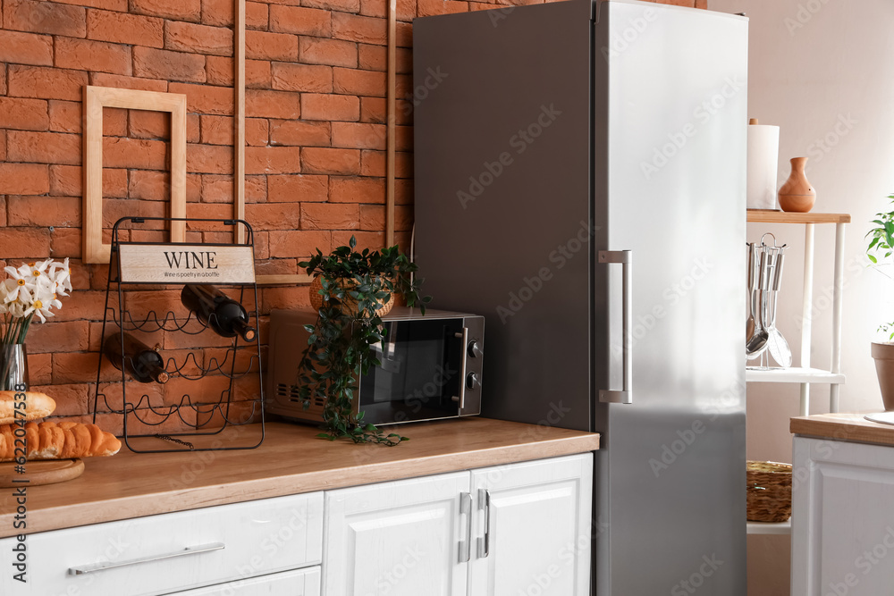 Interior of kitchen with stylish fridge, counters and microwave oven