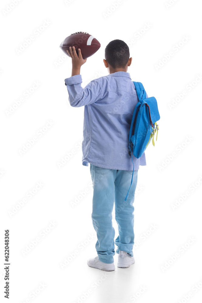 Little African-American schoolboy with rugby ball and backpack on white background, back view