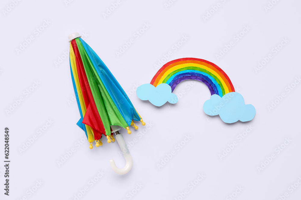 Paper rainbow with umbrella on white background. Weather forecast concept