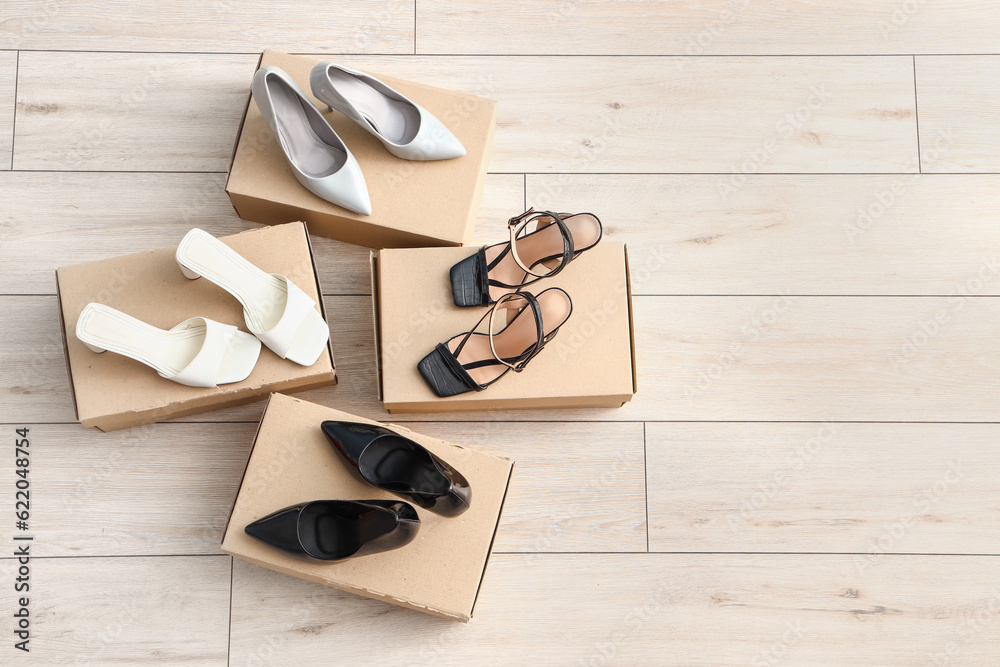 Cardboard boxes with heeled shoes on light wooden background