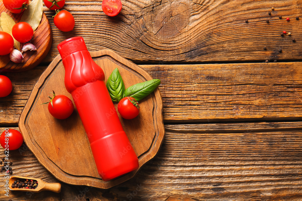 Board with bottle of ketchup and tomatoes on wooden background