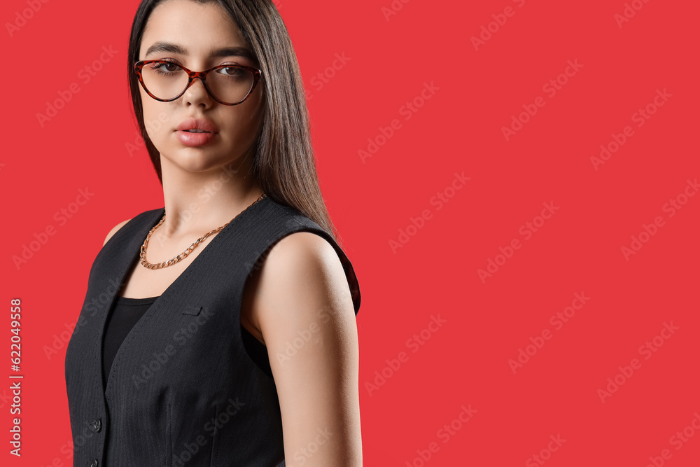 Fashionable young woman wearing glasses on red background