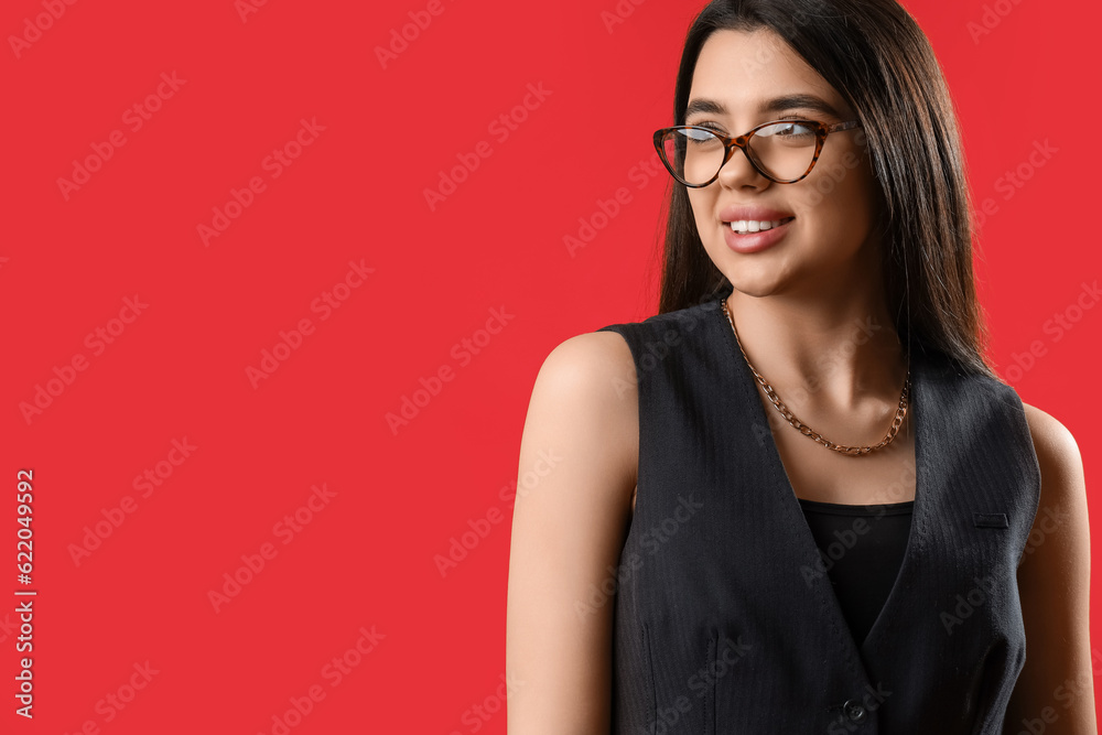 Fashionable young woman wearing glasses on red background