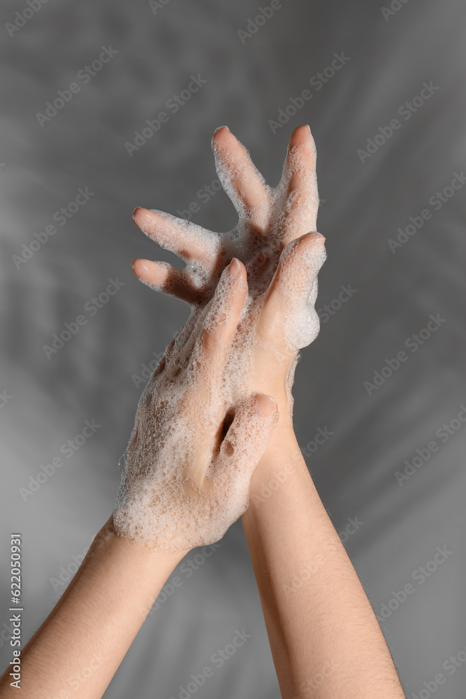 Hands in soap foam on grey  background