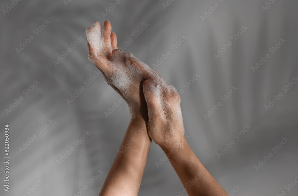 Hands in soap foam on grey  background