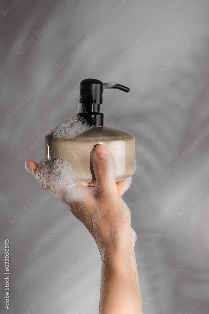 Hand with liquid soap on grey background