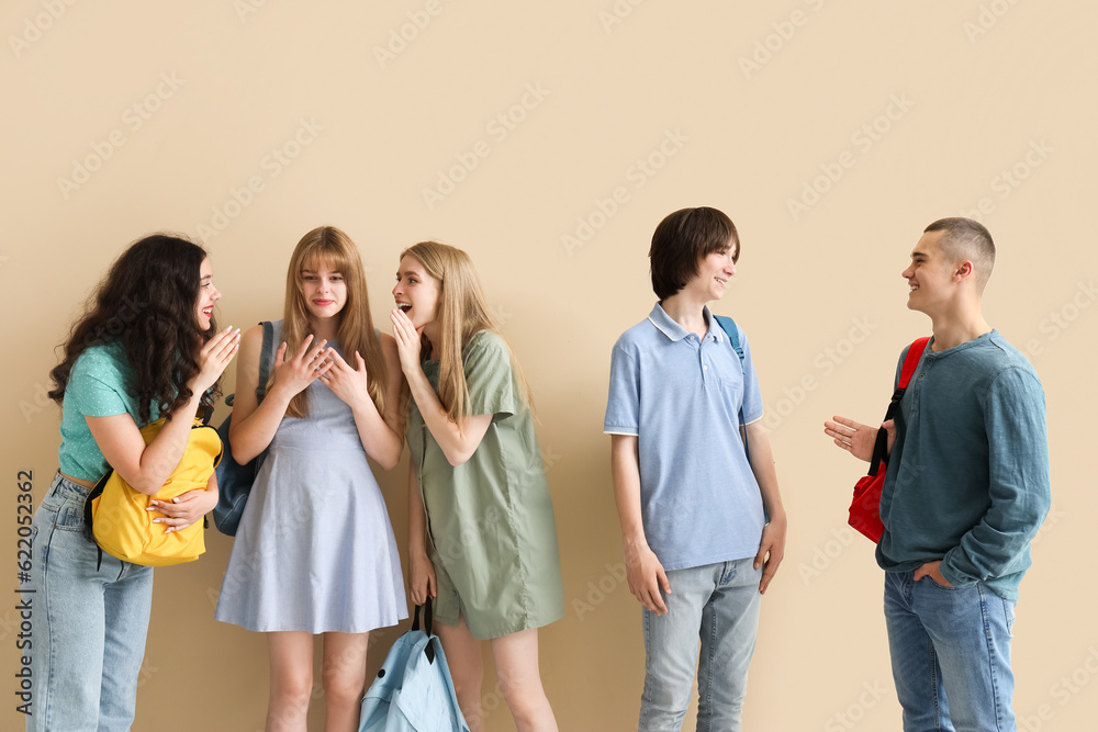 Group of students with backpacks near beige wall